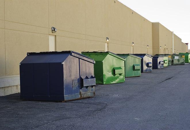 a row of yellow and blue dumpsters at a construction site in Brilliant